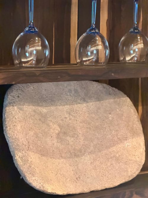 Tres lámparas colgantes de vidrio transparente sobre un cuenco de piedra texturizada en Ala Residencias Villa La Guardia, Chetumal
