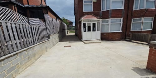 Driveway at Leeds Luxurious Stays villa in Moortown with brick building, white porch, and garden view