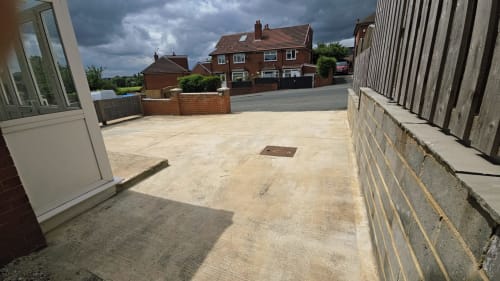 Spacious paved courtyard at Leeds Luxurious Stays villa in Moortown with brick buildings and cloudy sky