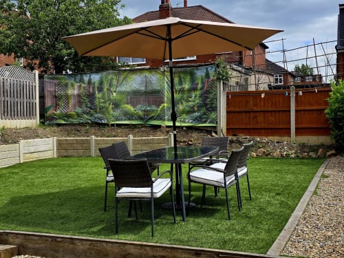 Beige umbrella shading black wicker dining chairs and table on lush green lawn in Borrowdale Brook villa garden at Leeds