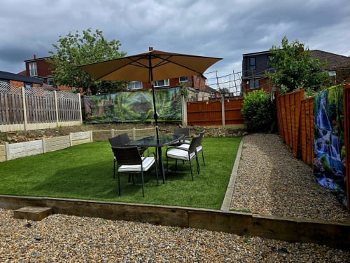 Borrowdale Brook villa garden with seating area, tan umbrella, and manicured lawn in Moortown