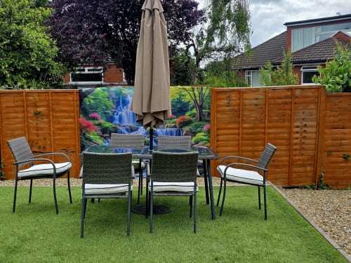 Garden seating area at Borrowdale Brook villa in Moortown with chairs, table, umbrella, and scenic waterfall backdrop