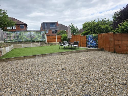 Spacious garden at Leeds Luxurious Stays villa with gravel patio, lawn seating area, wooden fencing and decorative panels in