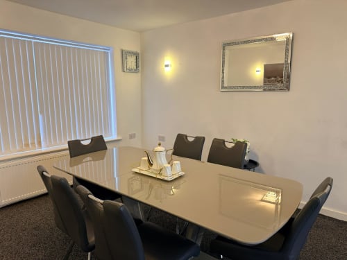 Modern dining room at Leeds Luxurious Stays with large table, black chairs, and garden view window in Moortown