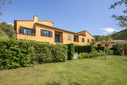 Villa mediterránea amarilla en Palafrugell con jardines cuidados, setos verdes y terrenos arbolados en Costa Brava, España