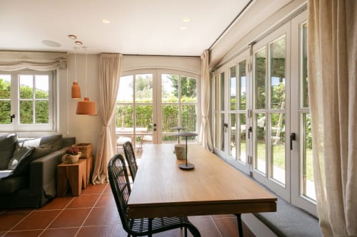 Amplio comedor y sala de estar iluminados con grandes ventanales, mesa de madera, sillas negras y acceso a la terraza exterior de la villa La Pastora