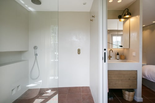 Baño moderno con ducha de obra, azulejos blancos, mueble de madera y grifería de latón en Finques Garcia Enrich