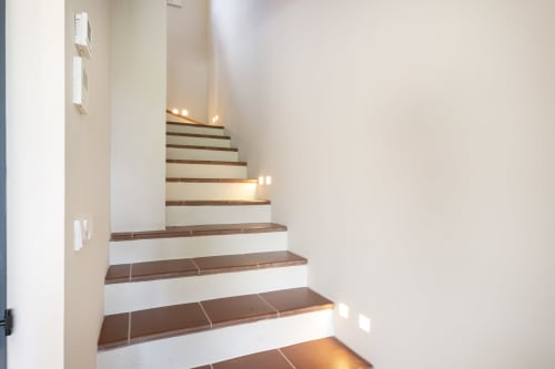 Escalera moderna de madera con contrahuellas blancas e iluminación empotrada en la villa de lujo La Pastora, Palafrugell