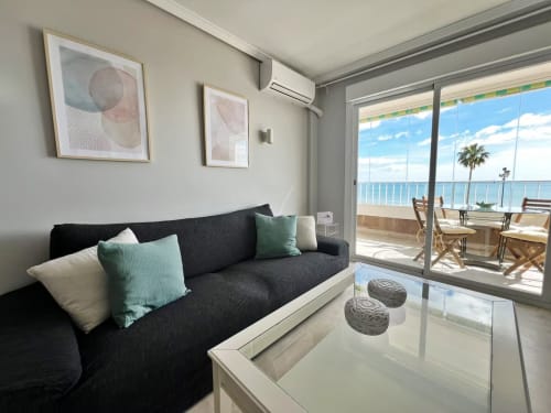 Moderno apartamento frente al mar en Fuengirola con vistas al Mediterráneo, sofá negro, mesa de cristal y terraza