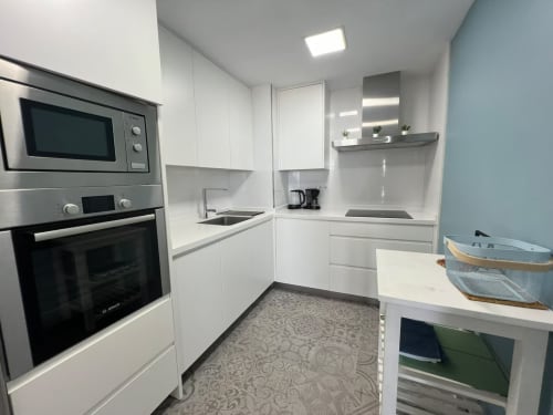 Cocina moderna blanca con electrodomésticos de acero inoxidable en apartamento frente al mar, Fuengirola