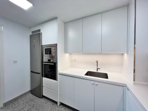 Cocina moderna con electrodomésticos de acero inoxidable, armarios blancos y vistas al mar en apartamento frente a playa de Fuengirola
