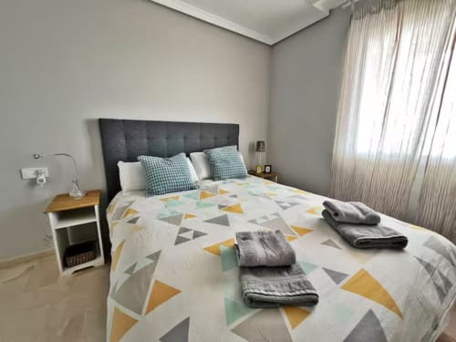 Dormitorio de apartamento frente al mar en Fuengirola con vistas al mar, ropa de cama geométrica, cabecero oscuro y diseño contemporáneo