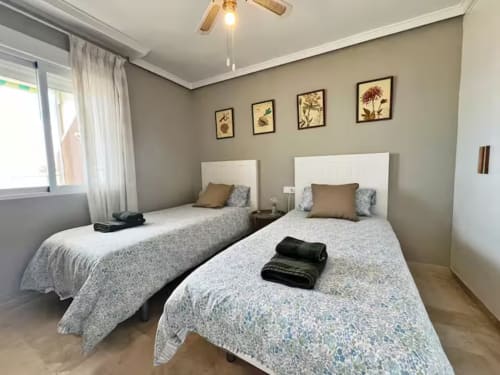 Habitación doble en apartamento frente al mar en Fuengirola con vistas al mar, cabeceros blancos y arte botánico en las paredes