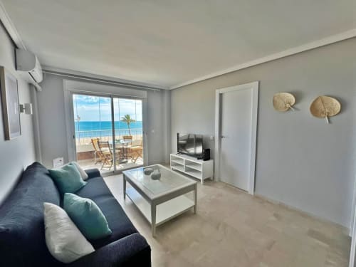 Apartamento frente al mar en Fuengirola con vistas al océano, salón moderno, sofá azul, TV y terraza orientada al mar