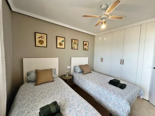 Luminoso dormitorio doble en apartamento frente al mar en Fuengirola con vistas al océano, armarios modernos, ventilador de techo y decoración costera.