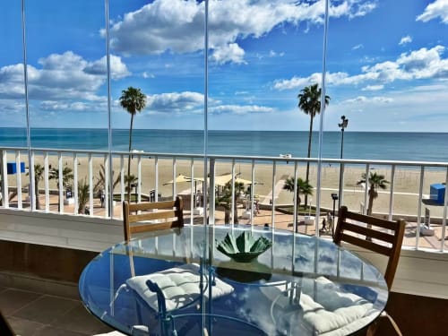 Comedor de apartamento frente al mar en Fuengirola con vistas panorámicas al mar, palmeras y playa arenosa a través de ventanales