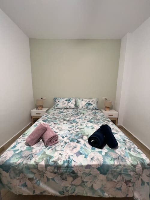 Dormitorio acogedor del apartamento Grupo Inmo House en Fuengirola con ropa de cama floral y mesitas de noche
