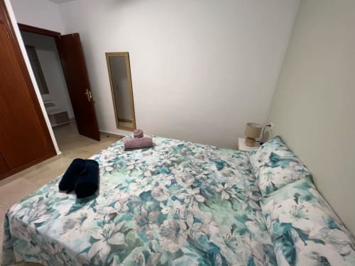 Acogedor dormitorio del apartamento Grupo Inmo House en Fuengirola con ropa de cama floral, espejo y puertas de madera