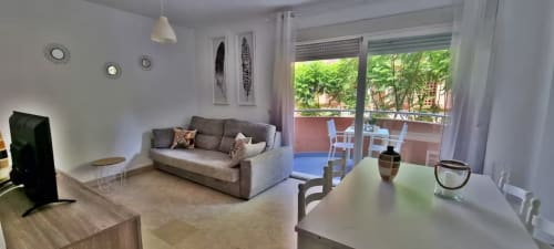 Moderno apartamento en Fuengirola con sofá gris, comedor, vistas a la terraza y luz natural