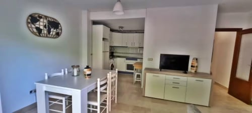 Moderno salón de apartamento en Fuengirola con cocina, mesa de comedor y televisión en estilo contemporáneo