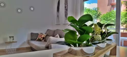 Sala de estar moderna con plantas en macetas, sofá gris y vistas al balcón en Fuengirola