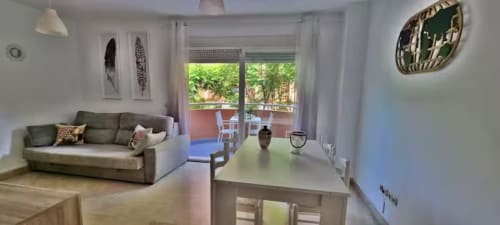Luminosa sala de estar diáfana con sofá gris, comedor y balcón con vistas a Playa de los Boliches en Fuengirola