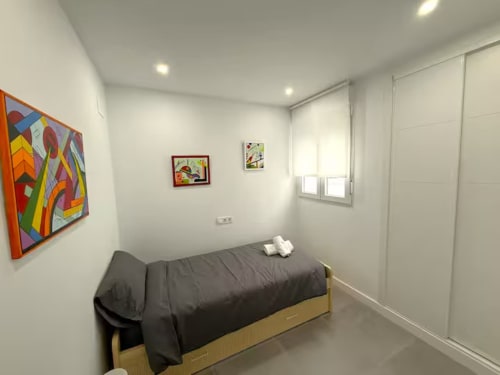 Moderno y luminoso dormitorio en Fuengirola con cama individual, obras de arte coloridas y vistas a la ciudad cerca de la playa