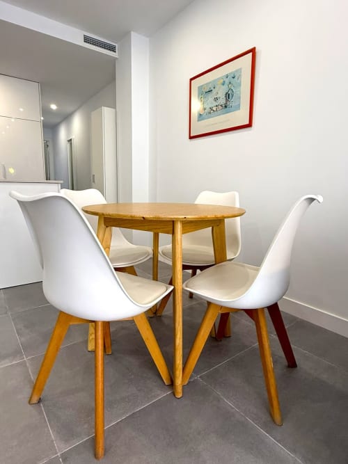 Comedor moderno con mesa redonda de madera y sillas blancas en apartamento de playa en Fuengirola