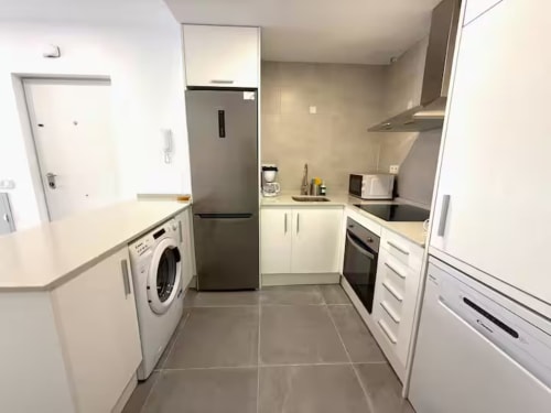 Cocina moderna en apartamento de Fuengirola con muebles blancos, nevera acero inoxidable, lavadora y estufa