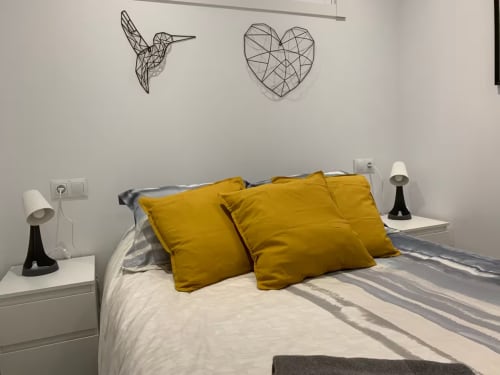Dormitorio moderno en apartamento de Fuengirola con almohadas amarillas en ropa de cama a rayas y arte geométrico en la pared