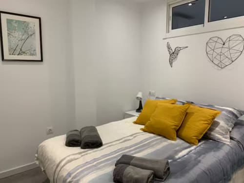 Dormitorio moderno en apartamento de Fuengirola con almohadas amarillas, ropa de cama a rayas, arte mural y vistas al mar