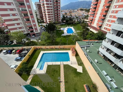 Vista aérea del complejo residencial Grupo Inmo House Fuengirola con piscina compartida, jardines cuidados y edificios con rayas rojas