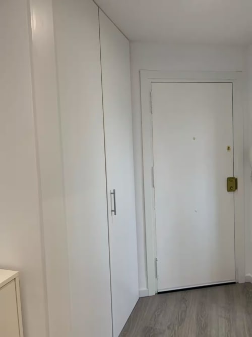 Pasillo moderno en blanco con armario empotrado y puertas en apartamento de Fuengirola con vistas al mar y servicios