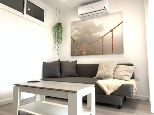 Sala moderna en apartamento de Fuengirola con sofá gris, mesa de café blanca, plantas colgantes y cuadros de paisaje