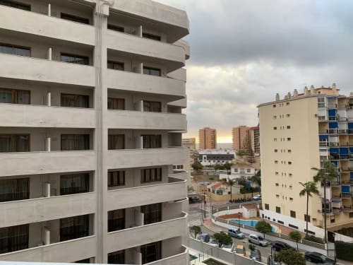 Vista de balcón en moderno apartamento de Fuengirola con piscina compartida, edificios adyacentes y zona residencial costera