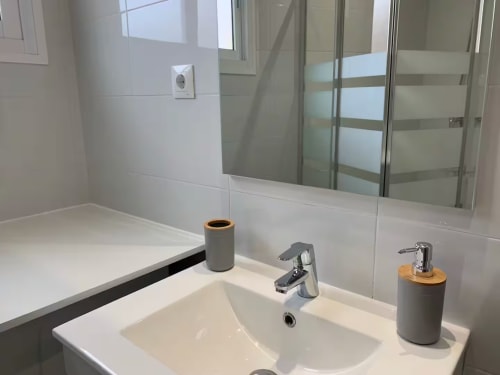 Vanidad de baño moderno con lavabo blanco, grifo cromado y artículos de tocador en apartamento de Fuengirola