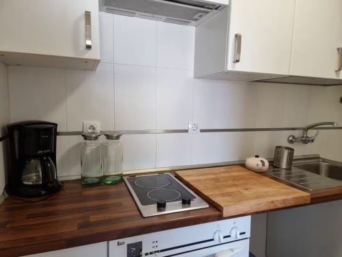 Cocina moderna en apartamento de Fuengirola con encimera de madera, placa de inducción y muebles blancos