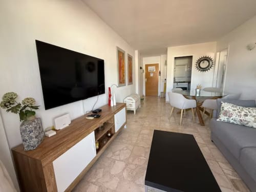 Salón moderno de apartamento en Fuengirola con televisor, zona de comedor y vistas a la montaña en Grupo Inmo House