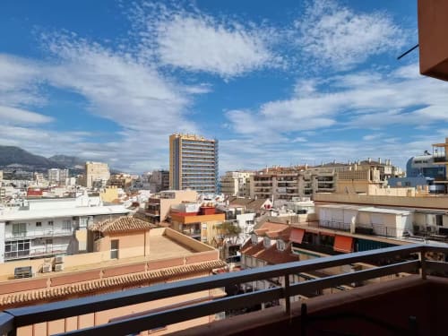 Vista de balcón del apartamento en Fuengirola con montañas, tejados de terracota y cielo azul mediterráneo