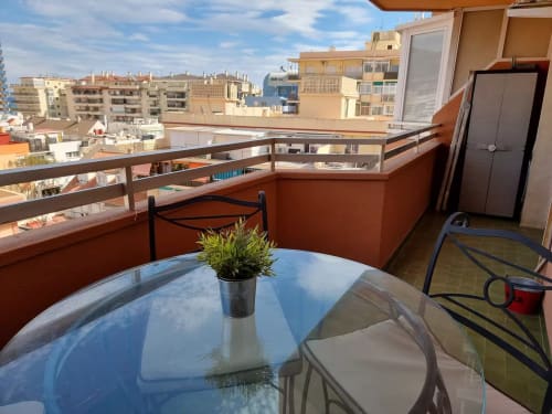 Terraza de apartamento frente al mar en Fuengirola con vistas a la ciudad, planta en maceta y arquitectura mediterránea.