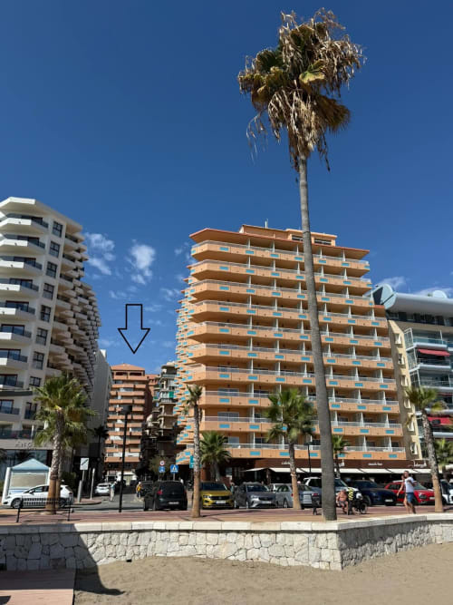 Edificio de apartamentos frente al mar en Fuengirola con palmeras y balcones modernos, señalando la ubicación de la propiedad