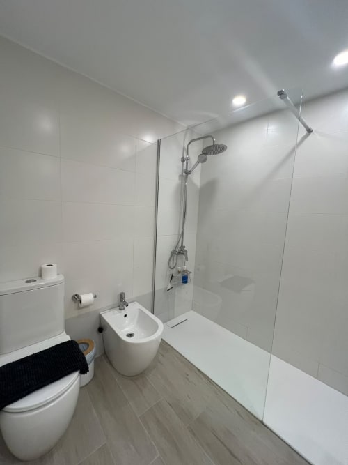 Baño moderno en apartamento de playa en Fuengirola con azulejos blancos, ducha a ras de suelo, bidé e inodoro