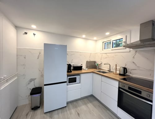Cocina moderna con muebles blancos, backsplash de mármol, encimeras de madera y electrodomésticos de acero inoxidable en playa de Fuengirola