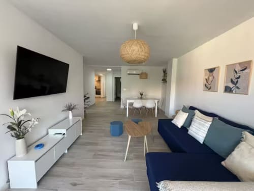 Moderno apartamento frente al mar en Fuengirola con salón abierto, sofá azul marino, comedor y TV de pantalla plana