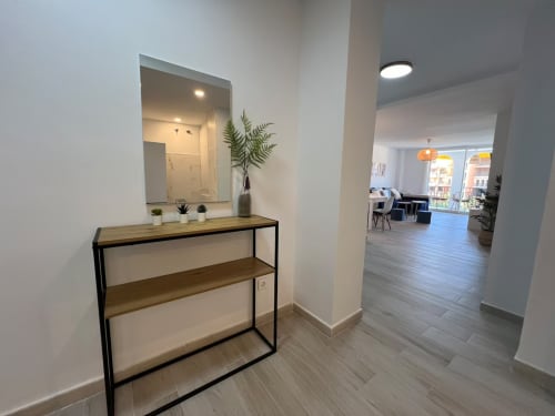 Entrada moderna del apartamento de playa en Fuengirola con consola, espejo, plantas y sala abierta