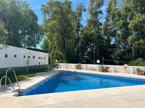 Piscina rectangular con agua azul y tumbonas en el apartamento de playa Grupo Inmo House en Fuengirola, rodeada de