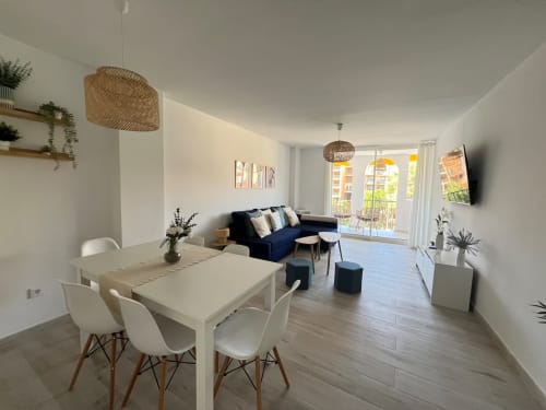 Luminoso apartamento en Fuengirola con mesa de comedor, sofá azul marino y balcón con vistas al jardín y la ciudad