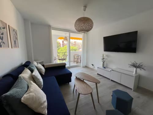 Salón moderno del apartamento de playa en Fuengirola con sofá azul, televisor de pantalla plana y balcón con vista al mar