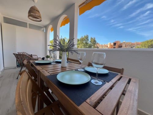 Elegante terraza de apartamento frente al mar en Fuengirola con mesa de comedor, vistas al jardín y mobiliario contemporáneo