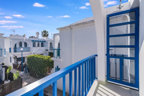Balcón de bungaló blanco y azul con vistas al jardín en Maspalomas, Gran Canaria